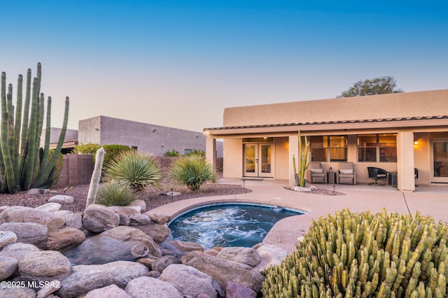 8183 N Sombrero Point Dr, Tucson, AZ 85743 - pool at dusk with french doors, an in-ground hot tub, a patio area, and outdoor lounge area