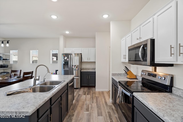 6494 E Brushback Loop, Tucson, AZ 85756 - kitchen with appliances with stainless steel finishes, a sink, white cabinets, light wood-type flooring, and light countertops