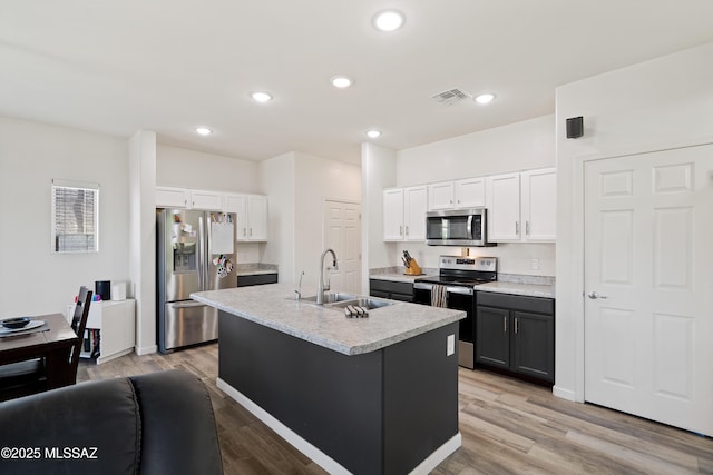 6494 E Brushback Loop, Tucson, AZ 85756 - kitchen with stainless steel appliances, a sink, white cabinetry, light countertops, and light wood-type flooring