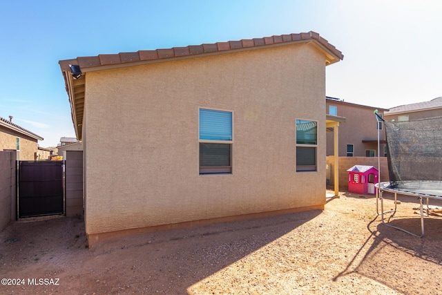 6210 S Open Desert Pl, Tucson, AZ 85706 - back of property featuring a trampoline, fence, stucco siding, and a gate