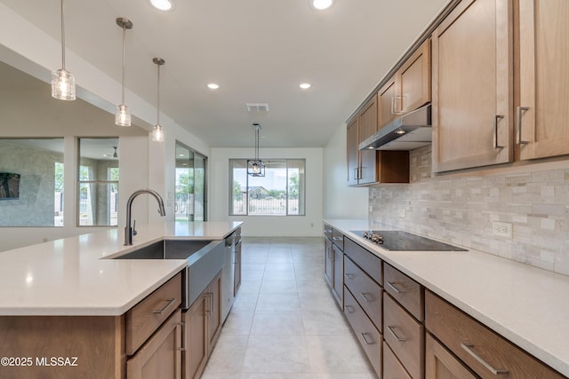 2559 E Wrightson View Dr, Green Valley, AZ 85614 - kitchen featuring under cabinet range hood, a sink, decorative backsplash, black electric cooktop, and hanging light fixtures