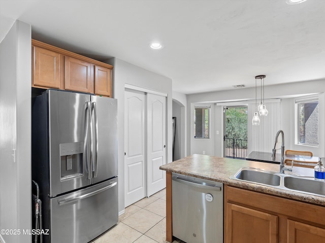 4801 E Canary Grass Dr, Tucson, AZ 85756 - kitchen featuring appliances with stainless steel finishes, a sink, arched walkways, light tile patterned floors, and brown cabinetry
