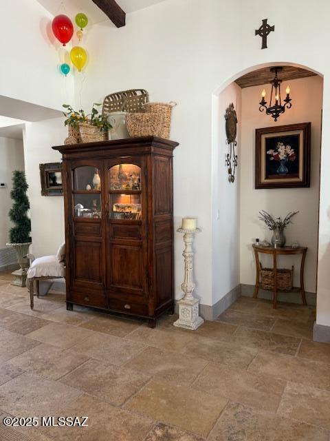 7774 E Cleary Way, Tucson, AZ 85715 - hall with stone tile flooring, arched walkways, baseboards, and a chandelier