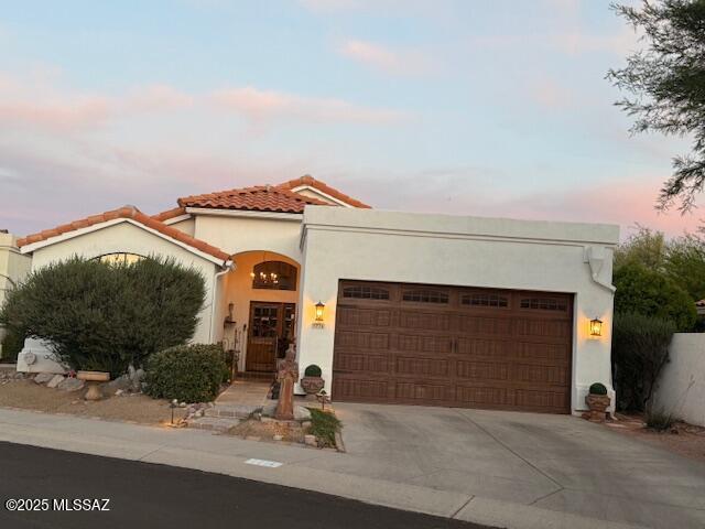 7774 E Cleary Way, Tucson, AZ 85715 - mediterranean / spanish house with an attached garage, stucco siding, concrete driveway, and a tile roof