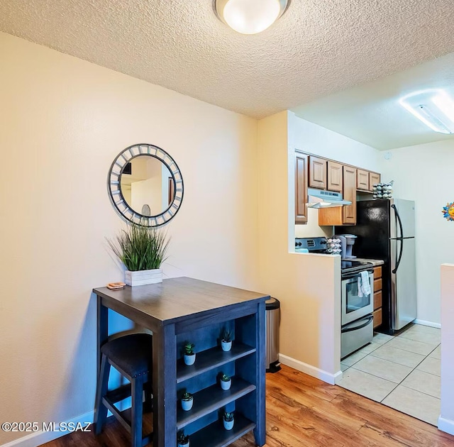 1745 E Glenn St Unit 133, Tucson, AZ 85719 - kitchen featuring stainless steel appliances, exhaust hood, light wood finished floors, a textured ceiling, and baseboards