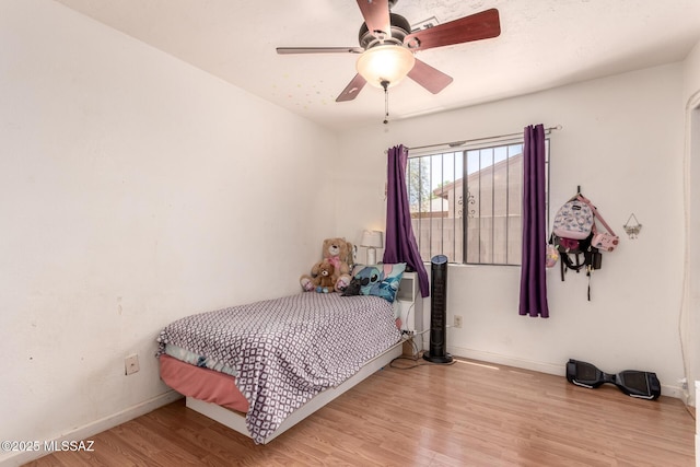 bedroom with wood finished floors, baseboards, and a ceiling fan