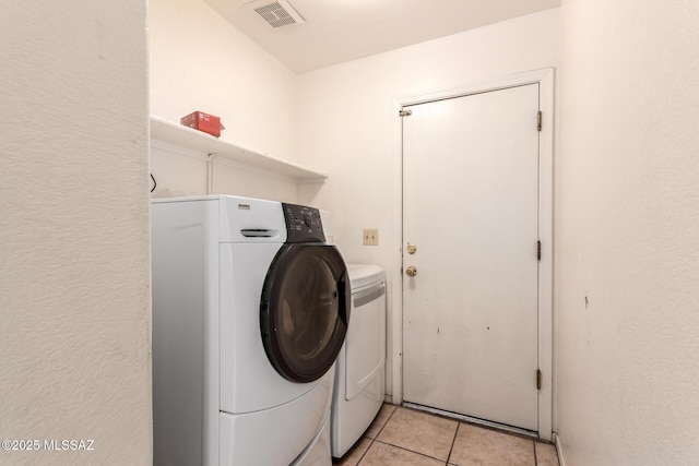 laundry area with separate washer and dryer and light tile patterned floors