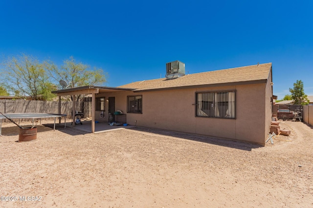 back of house featuring a fenced backyard, stucco siding, a trampoline, and a patio area