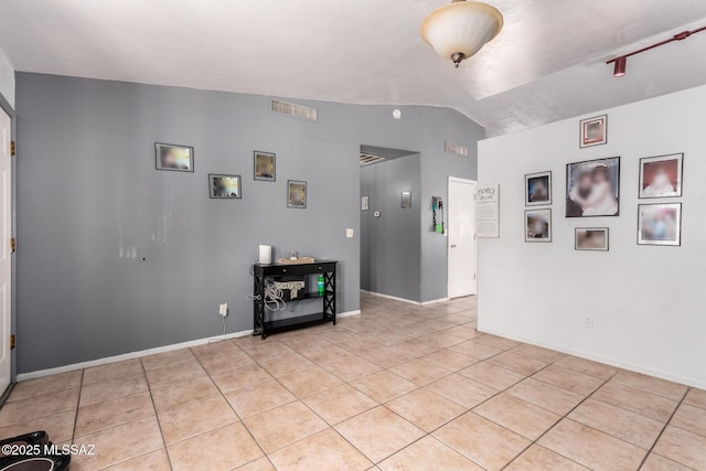 unfurnished room with light tile patterned flooring, vaulted ceiling, and baseboards