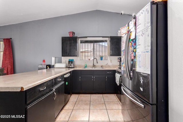 kitchen featuring freestanding refrigerator, a sink, a peninsula, light tile patterned floors, and gas range oven
