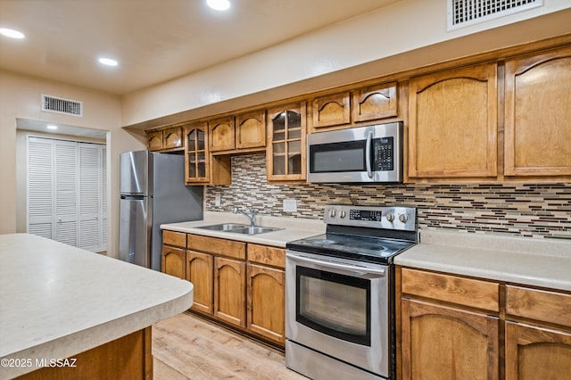 2002 E Pinon Dr, Tucson, AZ 85706 - kitchen featuring appliances with stainless steel finishes, light countertops, brown cabinetry, light wood finished floors, and recessed lighting