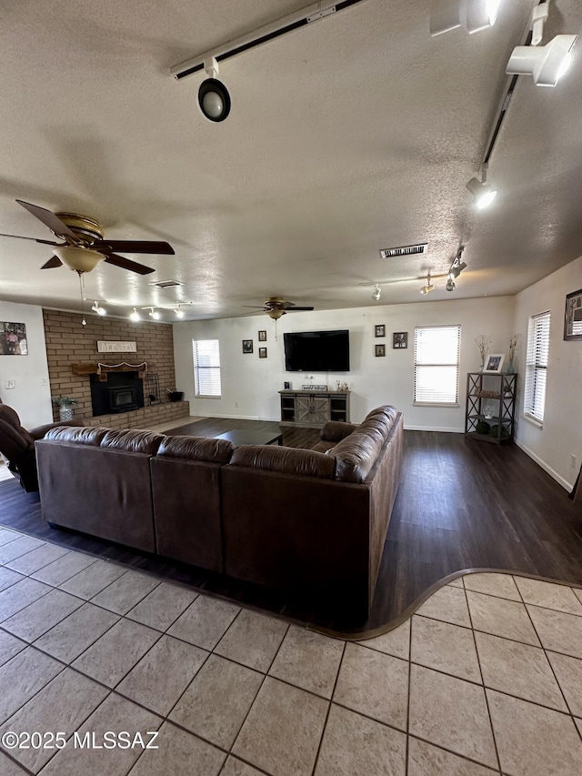 1609 S 12th Ave, Safford, AZ 85546 - living room featuring rail lighting, a brick fireplace, a ceiling fan, and a textured ceiling