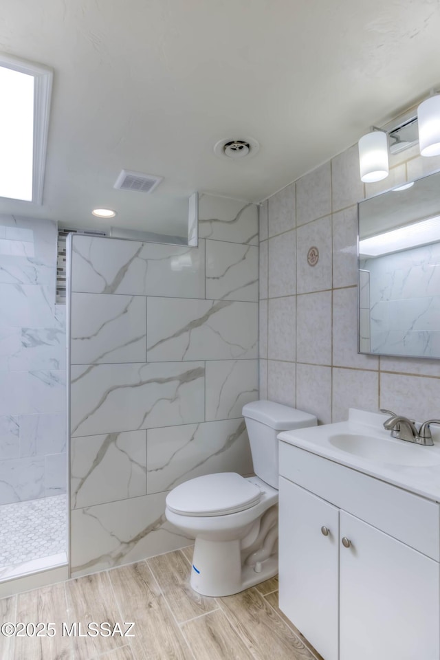 4842 E 27th St, Tucson, AZ 85711 - bathroom featuring tile walls, a marble finish shower, vanity, toilet, and wood finished floors