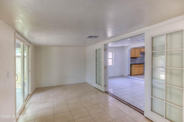4842 E 27th St, Tucson, AZ 85711 - empty room featuring arched walkways, light tile patterned floors, and baseboards