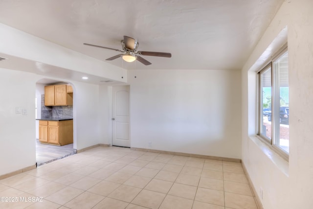 4842 E 27th St, Tucson, AZ 85711 - empty room featuring arched walkways, a ceiling fan, light tile patterned floors, and baseboards