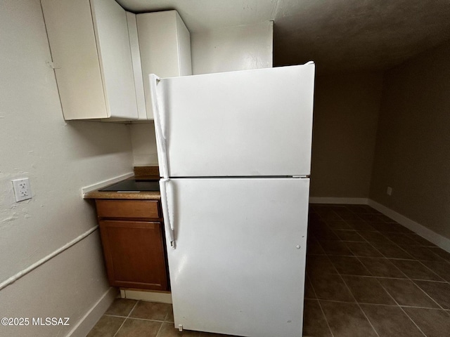 139 E 35th St, Tucson, AZ 85713 - kitchen with freestanding refrigerator, dark tile patterned floors, baseboards, and brown cabinets