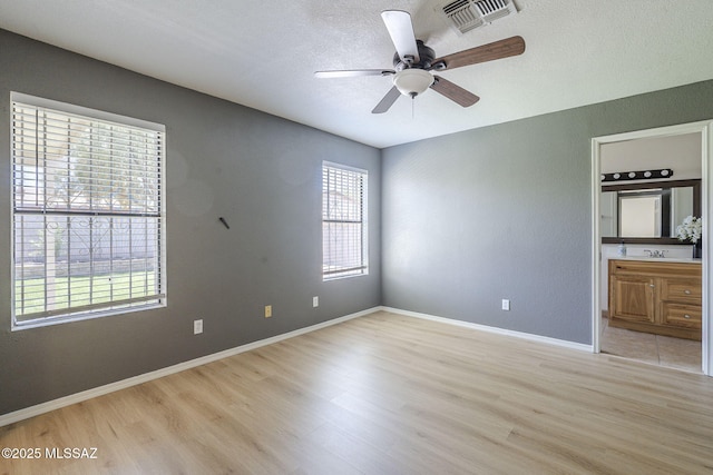 1741 W Maplewood Dr, Tucson, AZ 85746 - unfurnished bedroom with light wood finished floors, ensuite bath, a textured ceiling, baseboards, and a ceiling fan
