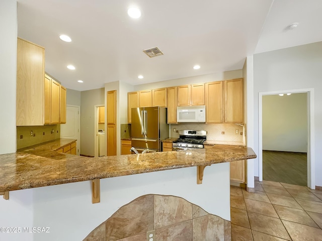 13401 N Rancho Vistoso Blvd Unit 190, Oro Valley, AZ 85755 - kitchen featuring appliances with stainless steel finishes, light brown cabinets, a peninsula, a kitchen bar, and decorative backsplash
