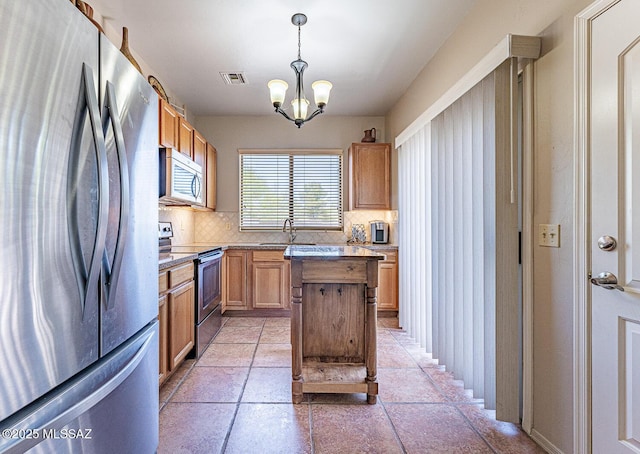 1012 W Via Del Placio, Green Valley, AZ 85614 - kitchen featuring stainless steel appliances, tasteful backsplash, a center island, a chandelier, and pendant lighting
