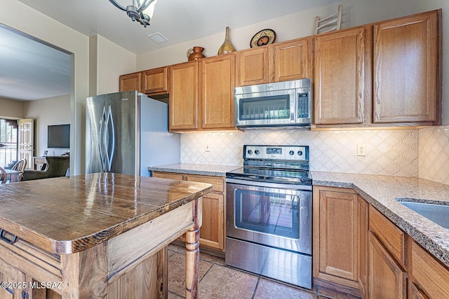 1012 W Via Del Placio, Green Valley, AZ 85614 - kitchen featuring appliances with stainless steel finishes, backsplash, a kitchen island, and dark stone counters