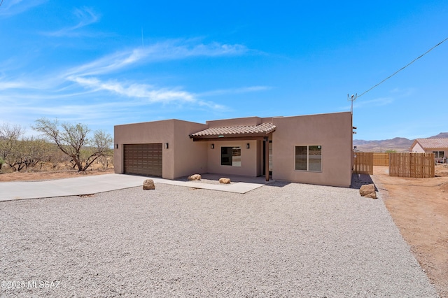 1814 Cajeme Ct, Rio Rico, AZ 85648 - pueblo revival-style home featuring an attached garage, stucco siding, driveway, a tiled roof, and a mountain view