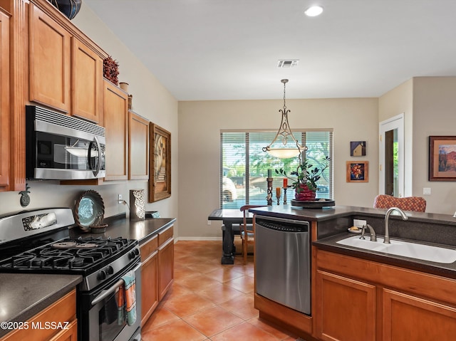 380 E Via Puente De La Lluvia, Sahuarita, AZ 85629 - kitchen with stainless steel appliances, a sink, dark countertops, brown cabinetry, and recessed lighting
