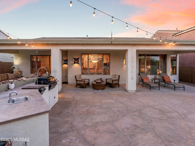 380 E Via Puente De La Lluvia, Sahuarita, AZ 85629 - back of property at dusk featuring a sink, exterior kitchen, and stucco siding