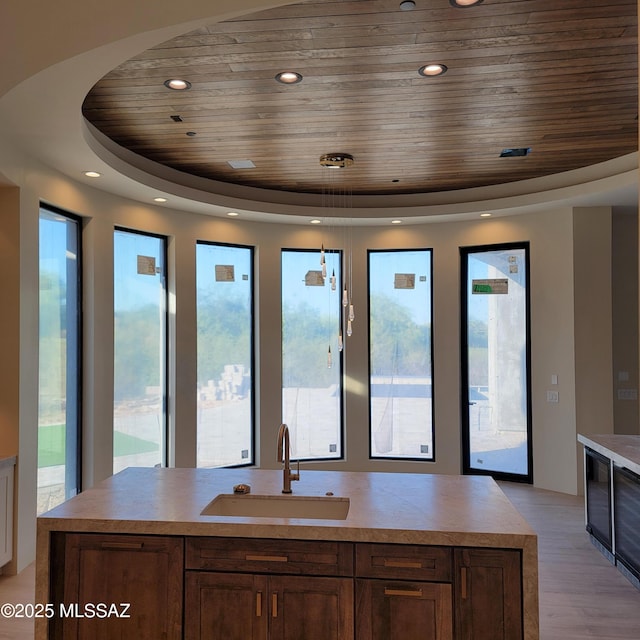 14295 N Silent Sky Pl, Marana, AZ 85658 - kitchen with wooden ceiling, a tray ceiling, plenty of natural light, light countertops, and light wood-style flooring