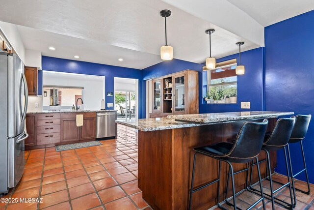2302 N Norton Ave, Tucson, AZ 85719 - kitchen with appliances with stainless steel finishes, a peninsula, a kitchen bar, a sink, and light stone countertops