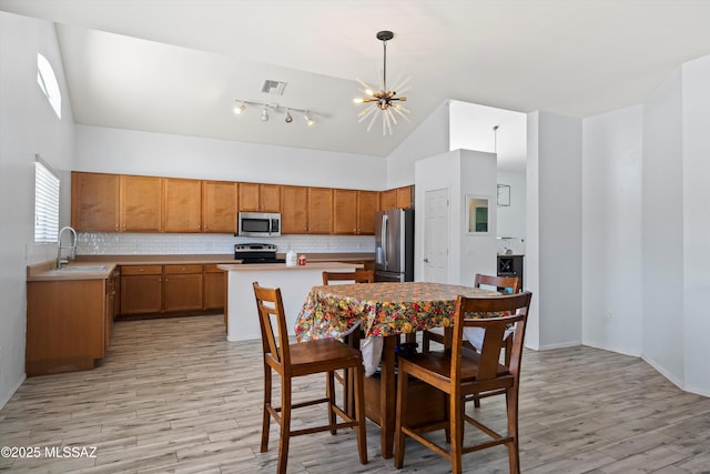 139 W Cheevers St, Vail, AZ 85641 - kitchen featuring appliances with stainless steel finishes, light wood-style floors, a chandelier, decorative backsplash, and high vaulted ceiling