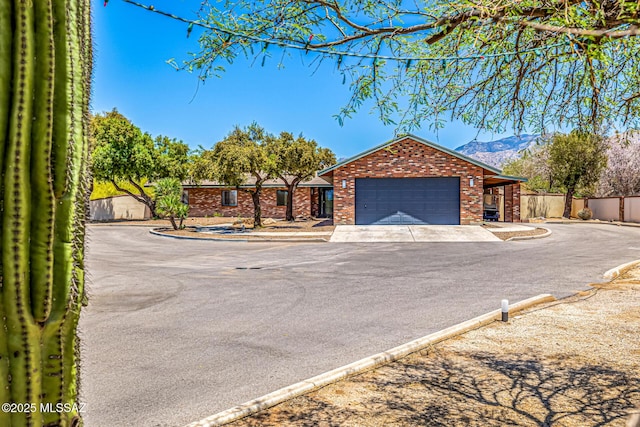 9840 N Desert Sky Rd, Tucson, AZ 85737 - single story home featuring an attached garage, brick siding, driveway, and a mountain view