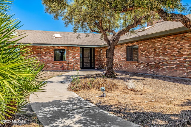 9840 N Desert Sky Rd, Tucson, AZ 85737 - doorway to property with roof with shingles and brick siding