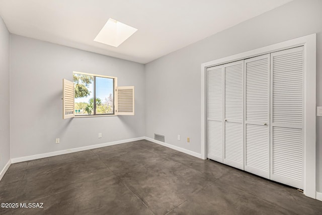 9840 N Desert Sky Rd, Tucson, AZ 85737 - unfurnished bedroom featuring a skylight, concrete flooring, baseboards, and a closet