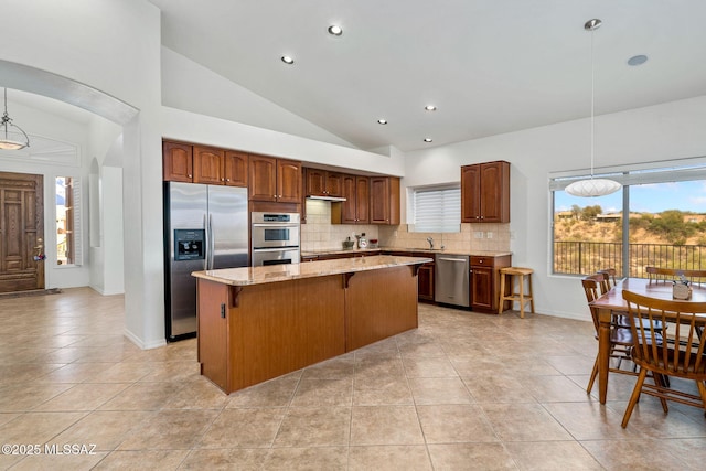 1048 E Rodda River Pl, Tucson, AZ 85718 - kitchen featuring appliances with stainless steel finishes, a kitchen island, decorative backsplash, a breakfast bar area, and light tile patterned flooring