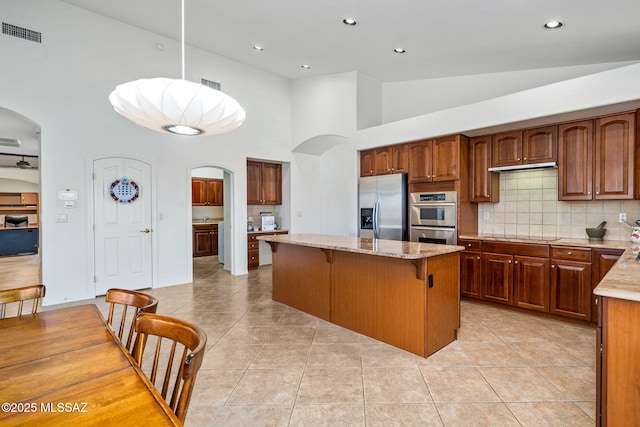 1048 E Rodda River Pl, Tucson, AZ 85718 - kitchen featuring arched walkways, appliances with stainless steel finishes, light tile patterned floors, a high ceiling, and recessed lighting