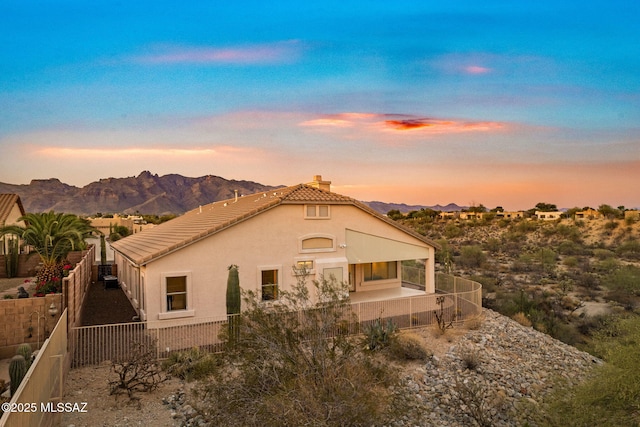 1048 E Rodda River Pl, Tucson, AZ 85718 - back of property at dusk with a chimney, a fenced backyard, a tile roof, a mountain view, and stucco siding