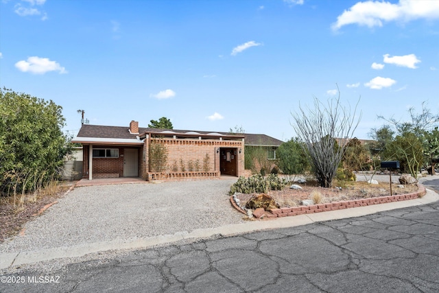 5247 E 6th St, Tucson, AZ 85711 - ranch-style house featuring gravel driveway, brick siding, and a chimney