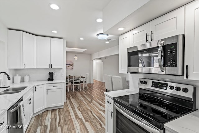 5247 E 6th St, Tucson, AZ 85711 - kitchen featuring appliances with stainless steel finishes, a sink, white cabinetry, recessed lighting, and light wood-style floors