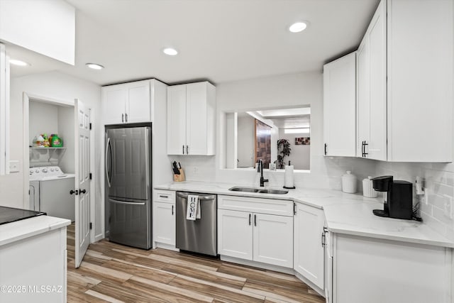 5247 E 6th St, Tucson, AZ 85711 - kitchen with appliances with stainless steel finishes, a sink, washer and dryer, white cabinetry, and decorative backsplash