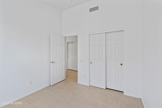 12122 N Sterling Ave, Oro Valley, AZ 85755 - unfurnished bedroom featuring baseboards, light tile patterned floors, a closet, and a towering ceiling