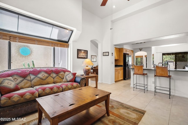 7133 E Grey Fox Ln, Tucson, AZ 85750 - living room with arched walkways, high vaulted ceiling, ceiling fan, light tile patterned floors, and baseboards