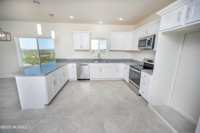 1681 Trampa Ct, Rio Rico, AZ 85648 - kitchen with stainless steel appliances, a peninsula, light stone countertops, a sink, and white cabinetry
