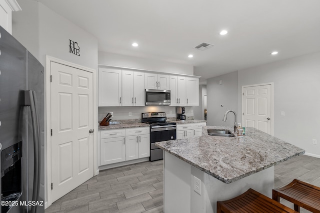 1941 E Greenlee Rd, Tucson, AZ 85719 - kitchen featuring appliances with stainless steel finishes, a sink, wood tiled floors, white cabinetry, and a breakfast bar area
