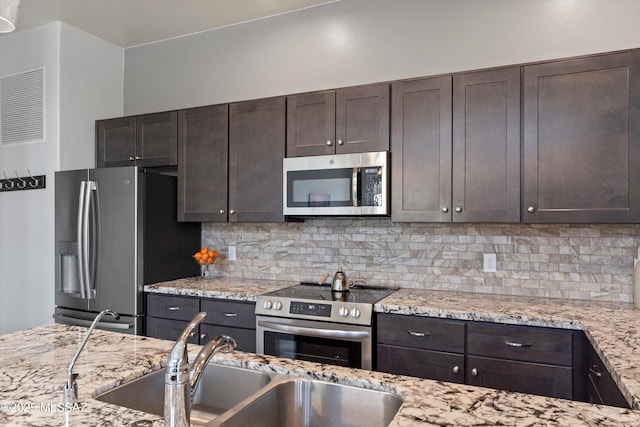 1759 E Via Colomba Bianca, Tucson, AZ 85737 - kitchen featuring stainless steel appliances, a sink, dark brown cabinets, and tasteful backsplash