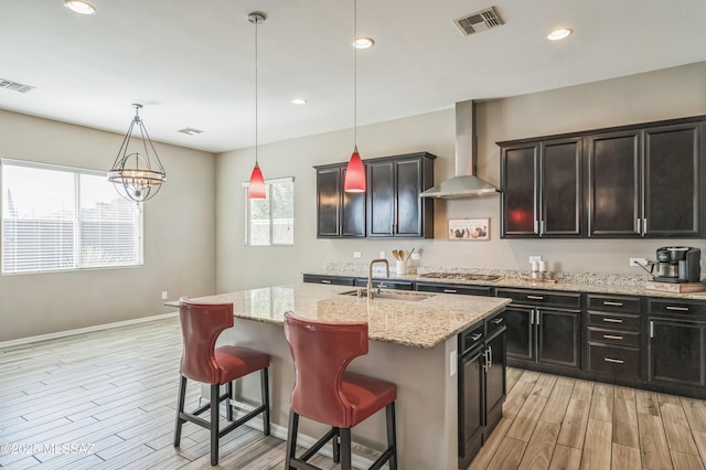 3022 S Open Range Way, Tucson, AZ 85713 - kitchen with a sink, wall chimney exhaust hood, light wood finished floors, an island with sink, and recessed lighting