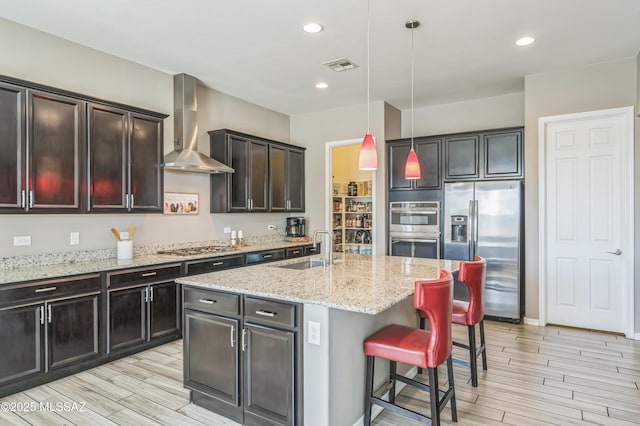 3022 S Open Range Way, Tucson, AZ 85713 - kitchen featuring appliances with stainless steel finishes, wall chimney range hood, a sink, wood finish floors, and a breakfast bar area