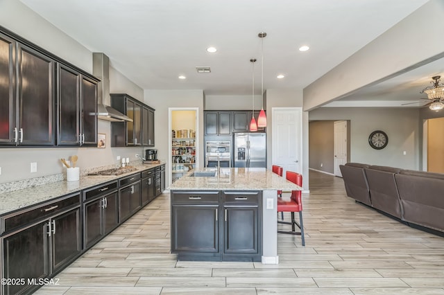 3022 S Open Range Way, Tucson, AZ 85713 - kitchen with appliances with stainless steel finishes, wall chimney exhaust hood, open floor plan, wood tiled floors, and recessed lighting