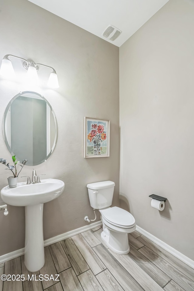 3022 S Open Range Way, Tucson, AZ 85713 - half bathroom featuring wood finished floors, toilet, baseboards, and a sink