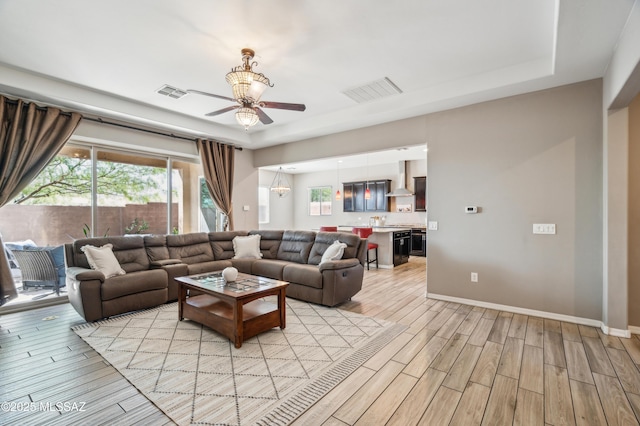 3022 S Open Range Way, Tucson, AZ 85713 - living room featuring a ceiling fan, light wood-style flooring, a tray ceiling, and baseboards