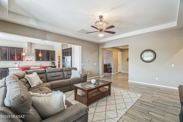 3022 S Open Range Way, Tucson, AZ 85713 - living area featuring baseboards, a ceiling fan, a raised ceiling, and light wood-type flooring